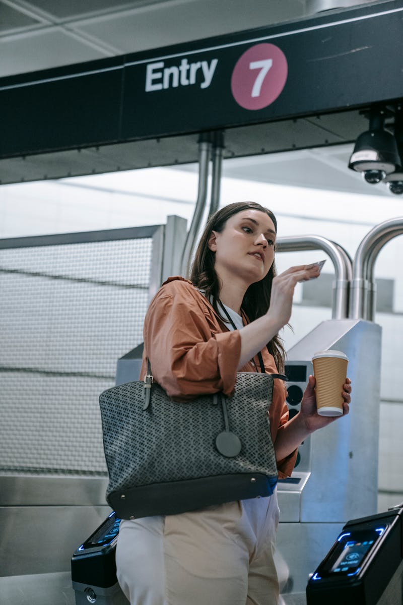 Young woman with coffee enters metro station. Captured in modern subway setting.
