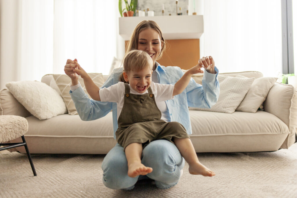Mujer y niño sonrientes, vestidos con ropa cómoda y moderna, en un entorno cotidiano (paseando, en casa, doblando ropa).